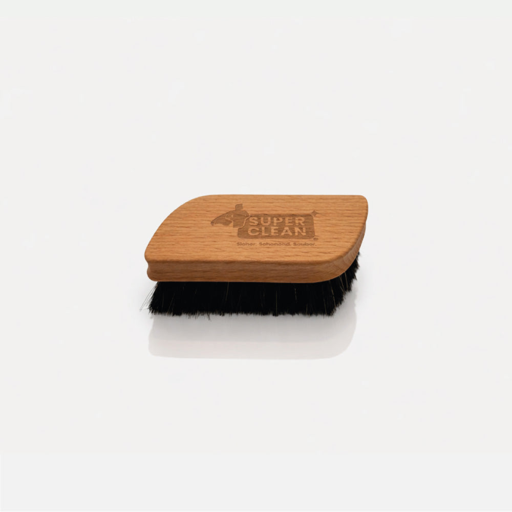 SUPER CLEAN Glanzbürste aus Holz mit dunklen Borsten und Logo-Gravur vor hellgrauem Hintergrund
