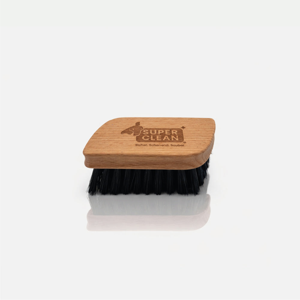 SUPER CLEAN Textilbürste aus Holz mit schwarzen Borsten und Logo-Gravur vor hellgrauem Hintergrund